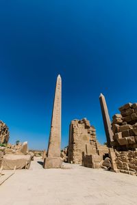 Low angle view of old ruins against clear blue sky