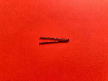 High angle view of hair clip on red table