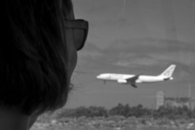 Rear view of woman with airplane flying in sky