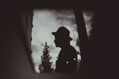 Side view of silhouette woman standing against window