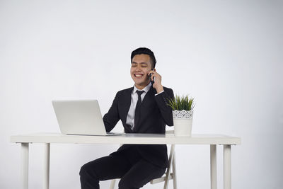 Young man using mobile phone while sitting on table