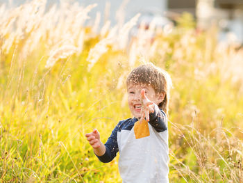 Cute toddler plays in field. smiling boy throws plant seeds in the air. outdoor leisure activity. 