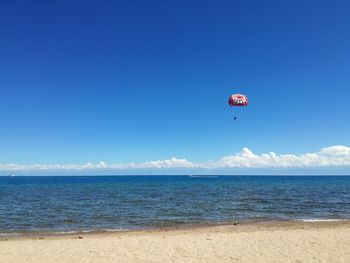 Distant view of parachute flying over sea seen from beach