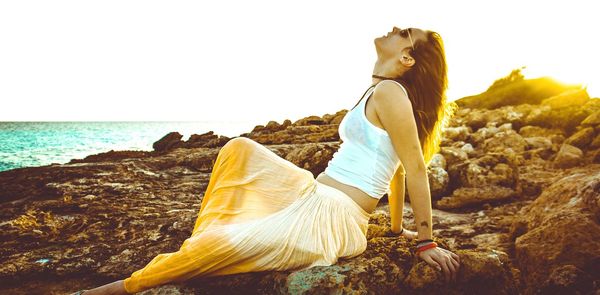 Side view of woman standing on beach against clear sky