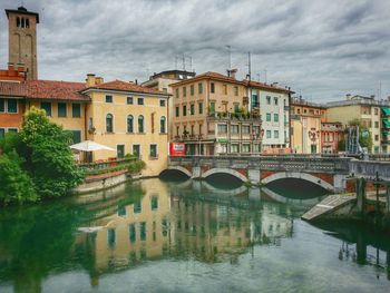 View of canal in city against sky