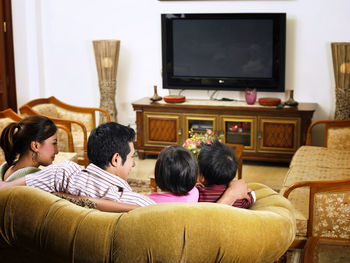 Rear view of family sitting on sofa at home