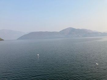 Scenic view of sea and mountains against clear sky