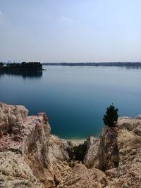 Scenic view of rocks by lake against sky