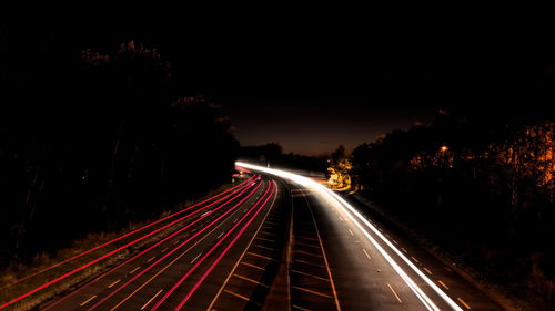 Light trails on road against sky at night