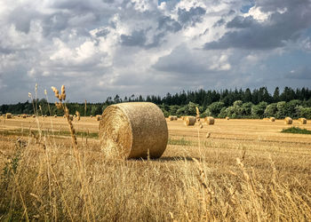 Hay bales on field against sky