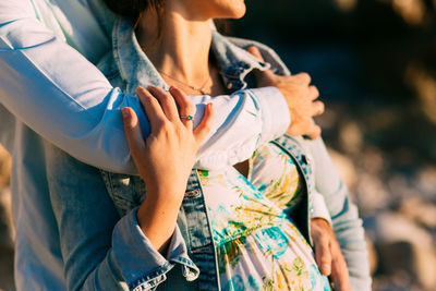 Midsection of man holding woman standing outdoors