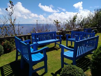 Deck chairs by sea against blue sky