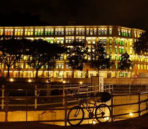Bicycle by illuminated building at night