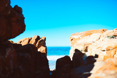 Rock formations by sea against blue sky