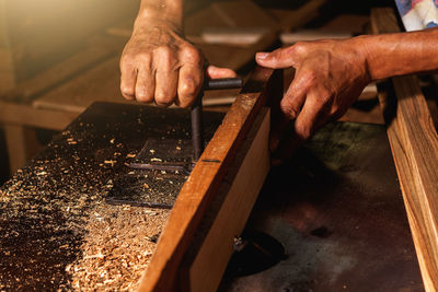 Close-up of a carpenter using a circular saw or a tool to cut wooden planks to make furniture  