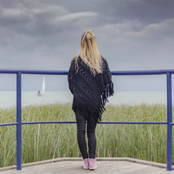 Rear view of woman standing on pier against sky