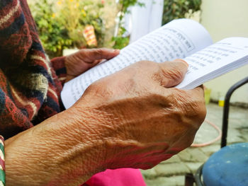 Cropped hands of senior person holding book in backyard