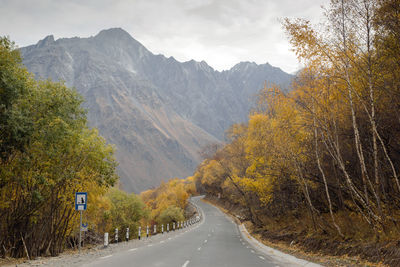 Road amidst trees and mountains against sky