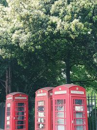 Red telephone booth against trees