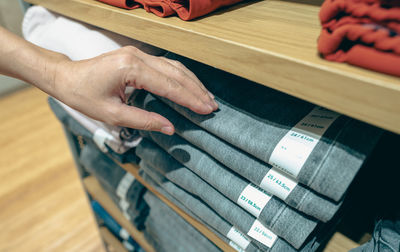 Woman shopping jeans in clothing store. woman choosing clothes. jeans on wooden shelves in clothing