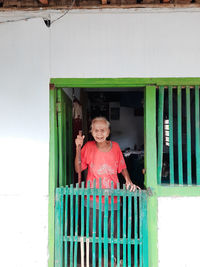 Portrait of smiling woman standing against wall