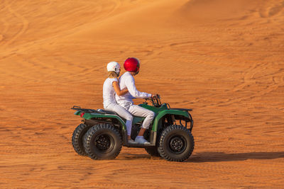 Side view of couple on quadbike at desert