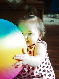 Portrait of cute toddler girl playing with balloon at home