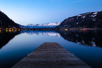 Scenic view of lake and mountains against clear blue sky