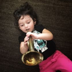 High angle of cute girl playing wind instrument