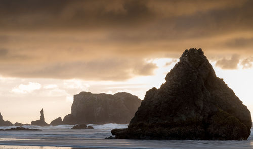 Rock formation by sea against sky during sunset