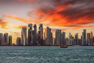 View of cityscape by sea against sky during sunset