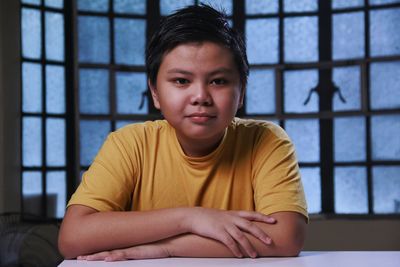 Portrait of boy sitting on table at home