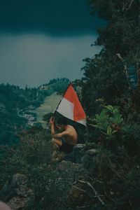 Woman holding umbrella on field against sky