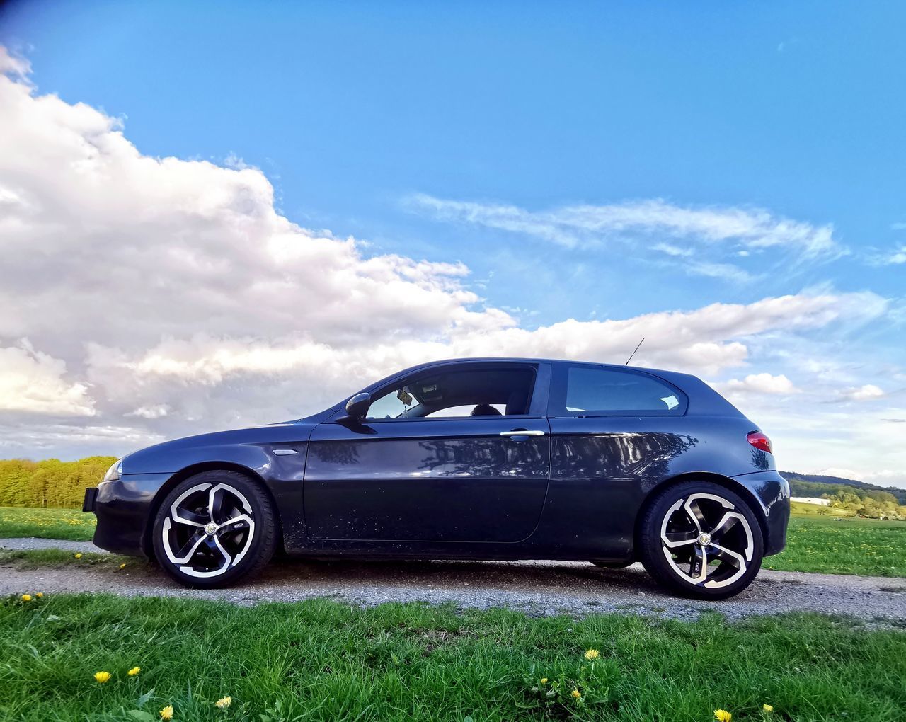 VINTAGE CAR ON FIELD AGAINST BLUE SKY