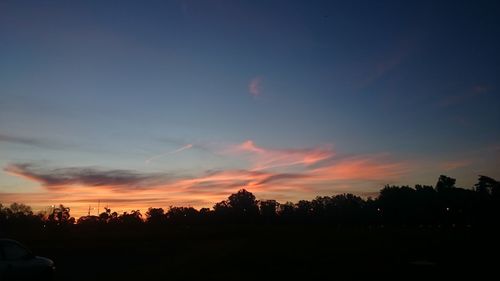 Silhouette trees on field against sky at sunset