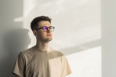 Young man standing against wall