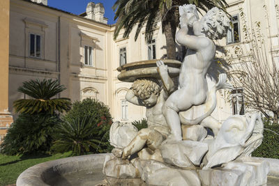 Statue by fountain against building