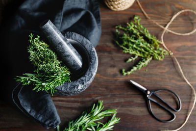 High angle view of mortar and pestle with herbs on table