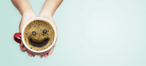 Midsection of man holding coffee cup against white background