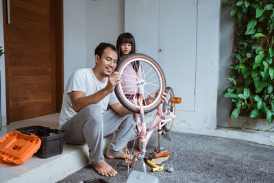 Father repairing bicycle with daughter at home