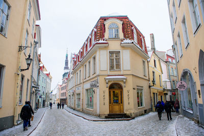 People walking on street amidst buildings in city