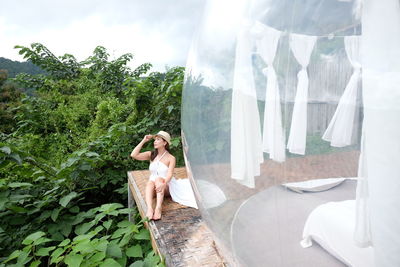 Rear view of woman standing in greenhouse