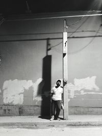 Man leaning on pole against wall
