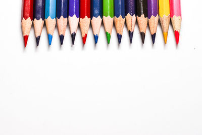 Directly above shot of colored pencils on white background