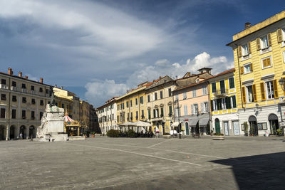 Street by buildings in town against sky