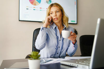 Young woman using mobile phone while sitting on table