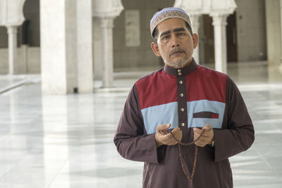 Portrait of man with necklace standing in mosque