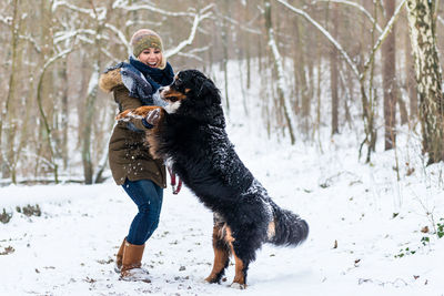 Woman playing with dog on snow covered land