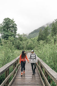 A young couple enjoys a hike on a boardwalk in the pacific northwest.