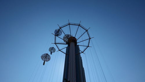 Low angle view of rollercoaster against clear blue sky